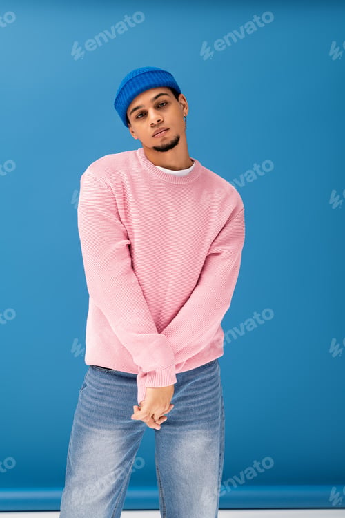 Preview: Handsome young man showcases contemporary fashion in a vibrant setting with stylish ease