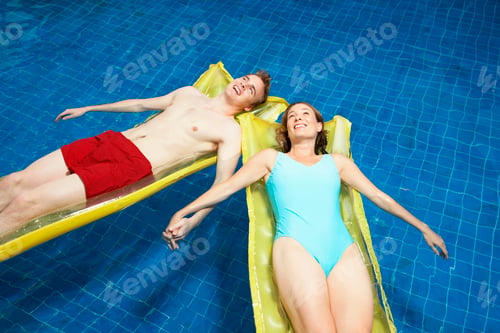 Preview: Couple lying on lylos holding hands