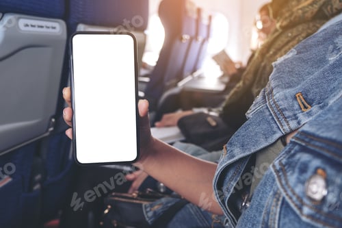 Preview: Mockup image of woman holding and showing a black smart phone with blank desktop screen in cabin
