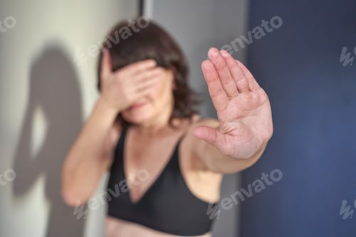 Preview: Female covering face with hand gesture in rejection position indoors