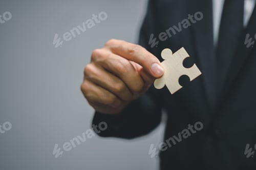 Preview: Concept of finding new solutions in a business, closeup of a man in a suit holding a jigsaw puzzle