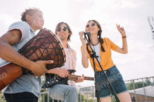 Preview: Young and happy street musicians playing music and singing in city