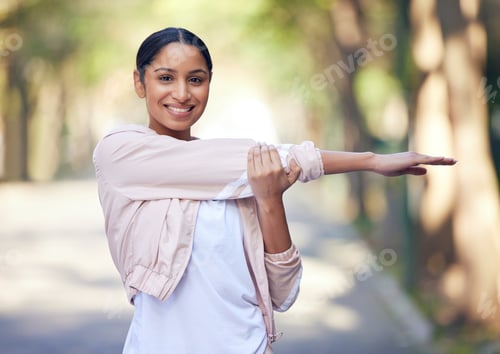 Preview: Portrait of a sporty young woman stretching her arms while exercising outdoors