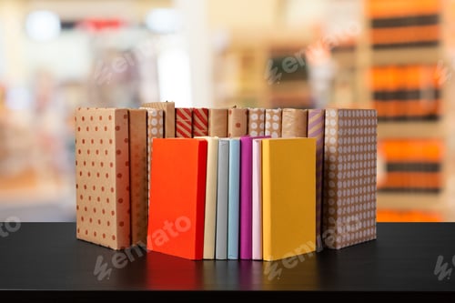 Preview: Stack of books on wooden table against blurred background
