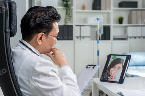 Preview: Asian doctor providing telehealth video consultation to online patient.