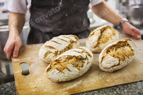 Preview: Baker holding tray with freshly baked loaves of bread.