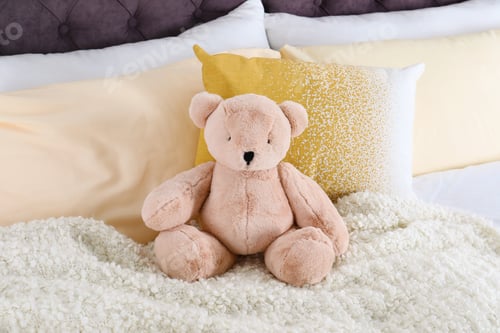 Preview: Cute teddy bear sitting on bed indoors