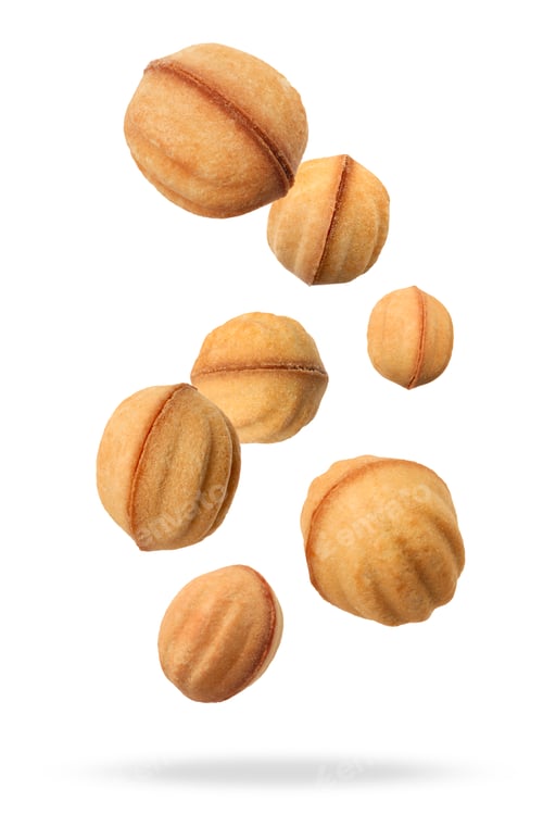 Preview: Many delicious nut shaped cookies with caramelized condensed milk falling on white background