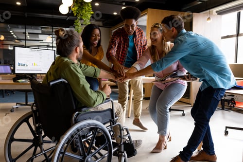 Preview: Diverse male and female colleagues stacking hands at casual office meeting