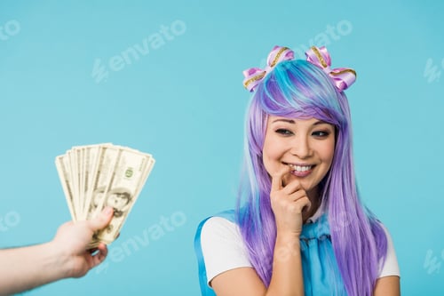Preview: Cropped view of man holding dollar banknotes and pensive asian anime girl isolated on blue