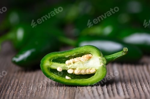 Preview: Half of green mexican jalapeno hot pepper on wooden table