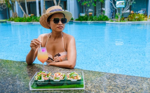 Preview: Asian women with hat and cocktail in hand relaxing in swimming pool, banner holiday vacation concept