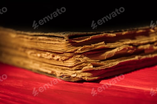 Preview: Very old ancient closed book on red wood surface.