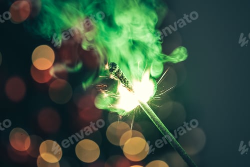 Preview: Close-up of green holiday sparkler in the dark