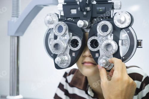 Preview: Young boy having eye test using phoropter.