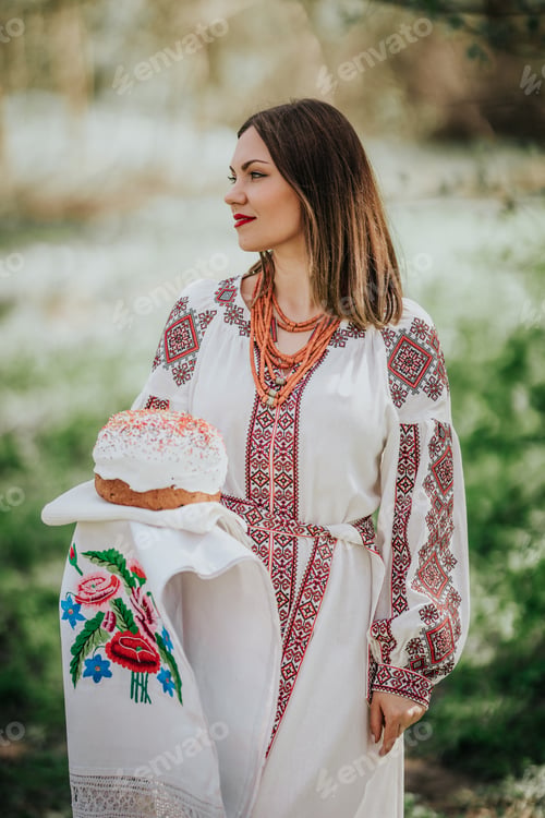 Preview: Ukrainian woman holding in hands Easter cake. Lady in embroidery vyshivanka dress on nature