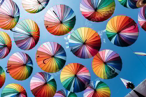 Preview: Umbrellas in rainbow color on blue sky background