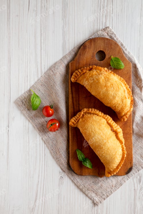 Preview: Homemade Deep Fried Italian Panzerotti Calzone on a rustic wooden board on a white wooden background