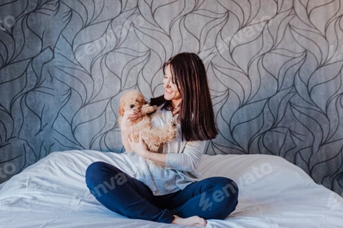 Visualização: retrato de um poodle de brinquedo marrom bonito com sua jovem dona em casa, durante o dia, dentro de casa.