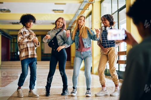 Preview: Playful high school students have fun while their friend is taking picture of them with cell phone.
