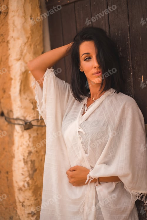 Preview: Brunette Caucasian girl in a white dress in a perched in a house in the desert