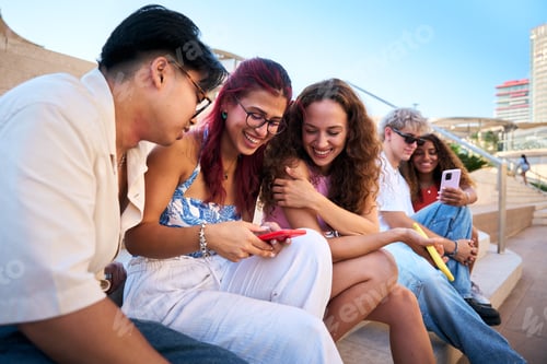 Preview: Young people sharing funny content on smartphone in urban setting