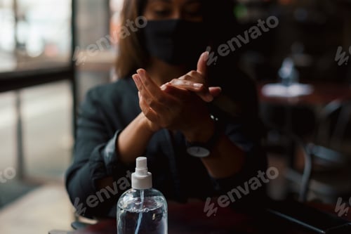 Preview: Young woman washing hands with sanitiser in coffee shop