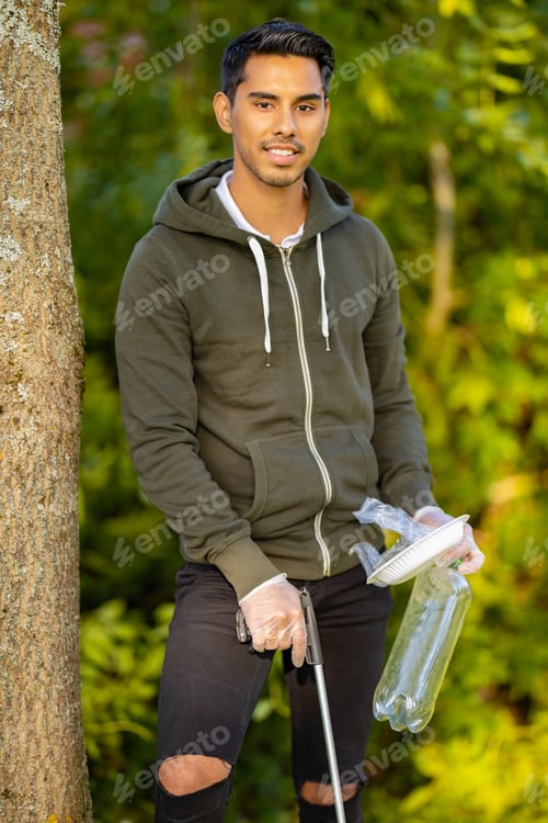 Preview: Proud environment protection volunteer holding garbage and mechanical grabber