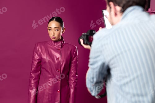 Preview: Fashionable asian brunette woman in a purple leather jacket posing for a man's photo in front of a