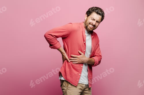 Preview: Young Caucasian man feeling muscle spasm in the back over pink background