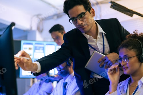 Preview: Professional team collaborates in tech office. Manager points at monitor screen