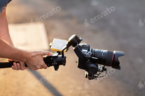 Preview: Operator using modern technology: stabilizer for camera and app on mobile phone for video streaming