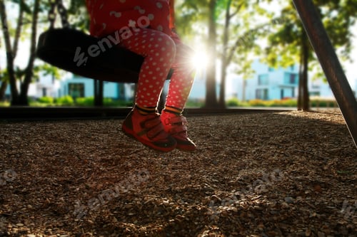 Preview: Little Girl On Swings At Sunset In Outdoor Playground
