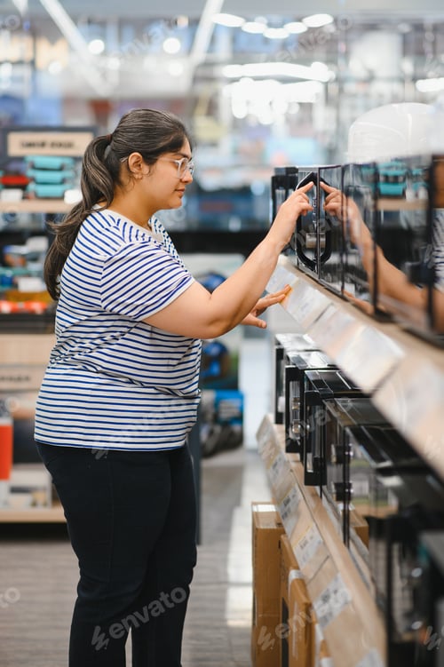 Preview: Indian Woman shopping for microwave in appliances store.