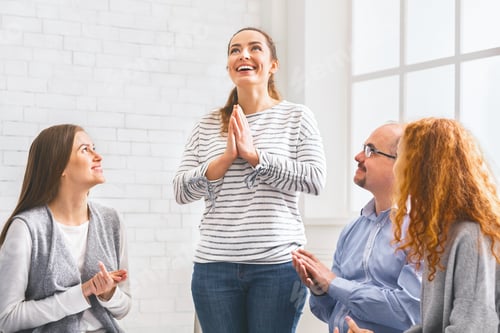 Preview: Community members clapping to woman, supporting her at therapy group meeting