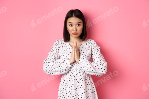 Preview: Cute asian girl asking for help, begging for favour and looking innocent at camera, pleading against