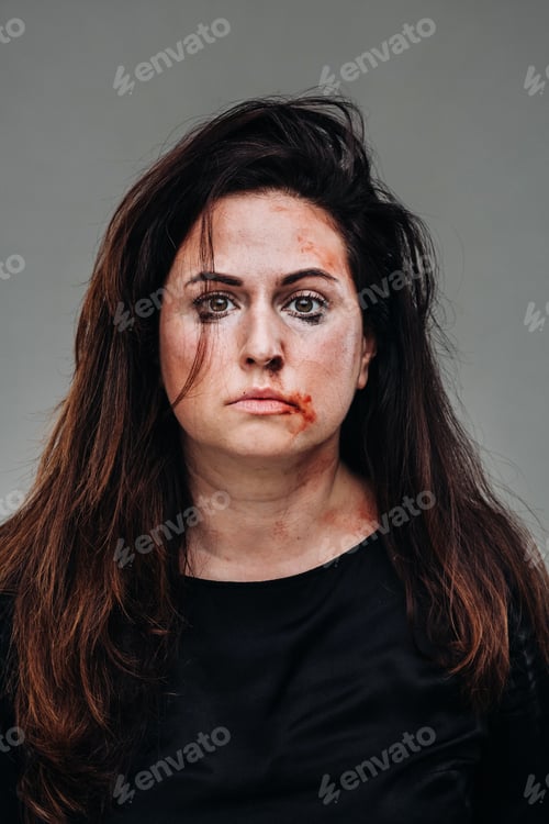 Preview: a battered woman in black clothes on an isolated gray background. Violence against women