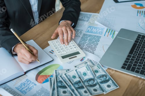 Preview: cropped image of financier using calculator and writing something to notebook in office