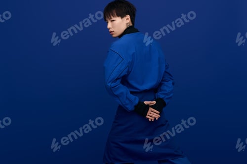 Preview: Young handsome man in stylish blue outfit poses confidently against a solid color background