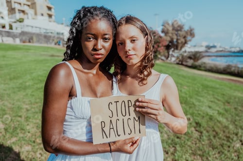 Preview: Two young women holding a sign that says "Stop Racism", confident gaze, integration concept