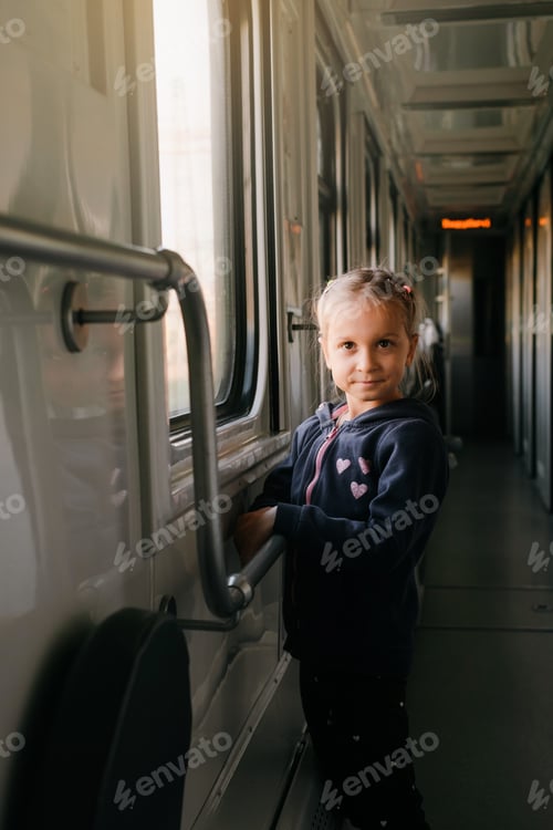 Vista previa: Child in train looking though train window on sunset