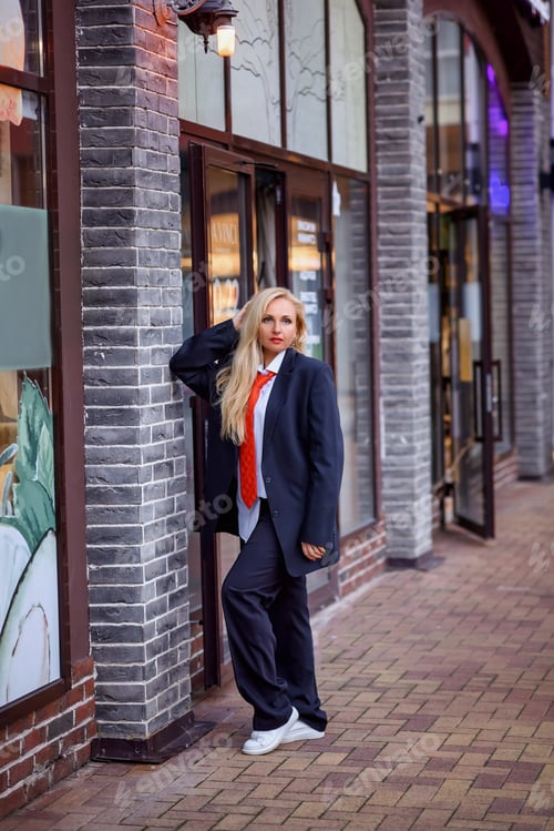 Preview: beautiful caucasian girl in a man's suit and tie in the old city at sunset