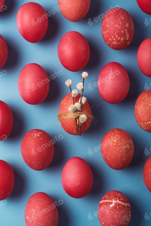Preview: Red Easter eggs float on blue background, one egg holds pussy willow with twine