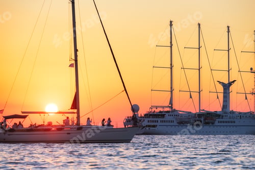 Preview: Sailing yachts during sunset. Silhouettes of yachts against the sun.
