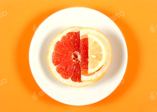 Preview: Fresh Grapefruit Lying On A White Plate That Stands On An Orange Background