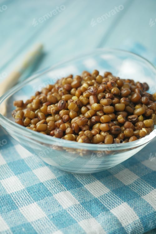 Preview: A beautiful glass bowl filled with brown sprouted mung beans sitting on a blue checkered tablecloth