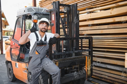 Preview: Warehouse worker gesturing thumbs up near forklift and lumber