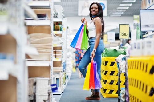 Preview: Beautiful african american woman holding multicolored shopping bags in a store.