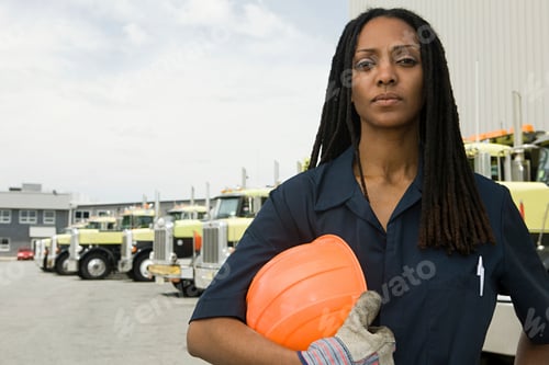 Preview: Confident female worker with hard hat at a truck depot