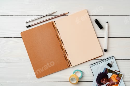 Preview: Creative workspace with open notebook, stationery, and decorative items on a wooden table